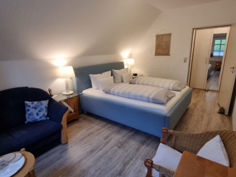 Ansicht eines Schlafzimmers mit Doppelbett, Kleiderschrank, anbei ein großes Sofa mit Kaffeetisch