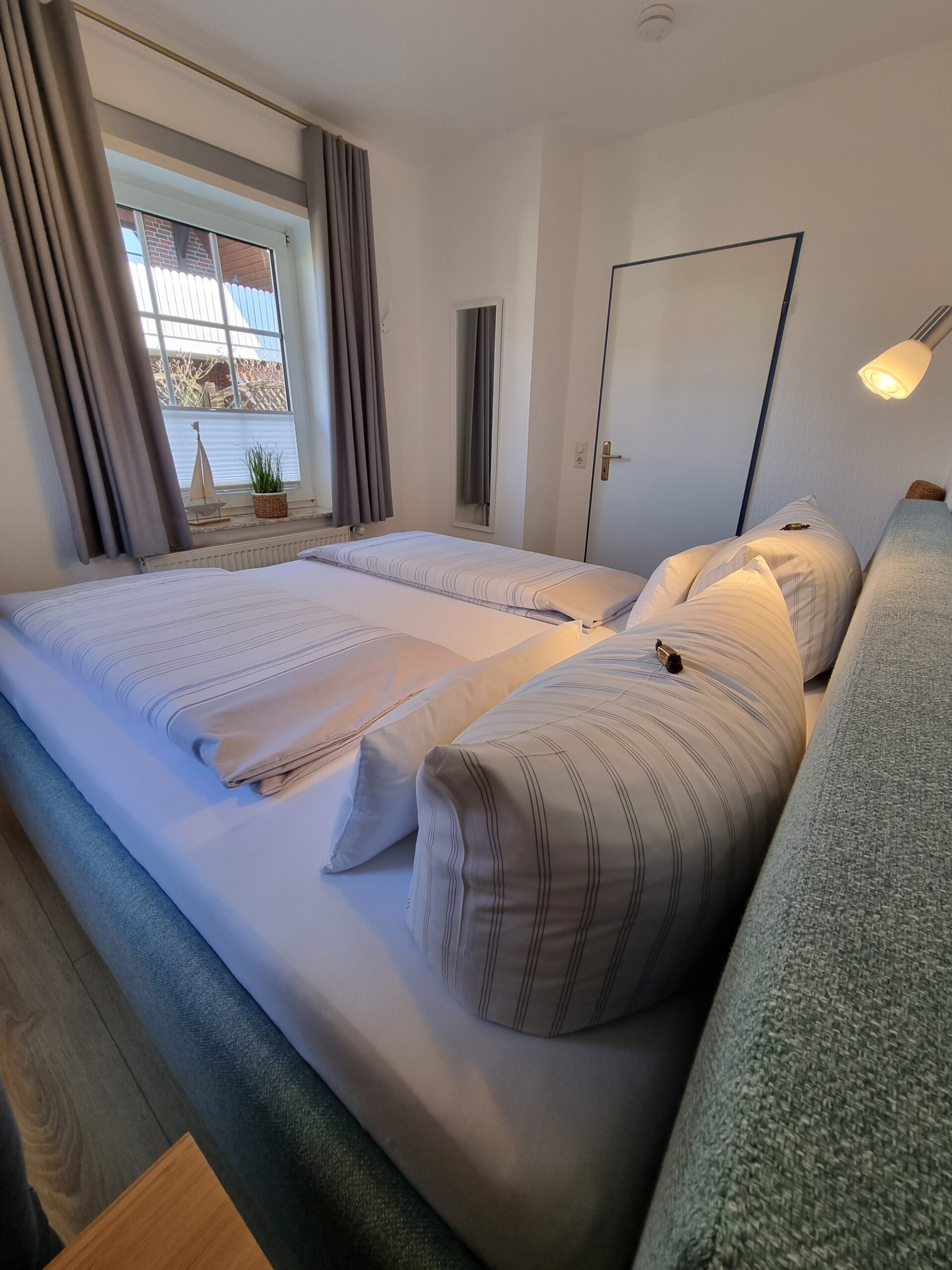 Doppelbettzimmer mit Sicht auf ein Fenster in einer Hotelsuite im Hotel Friesenhuus