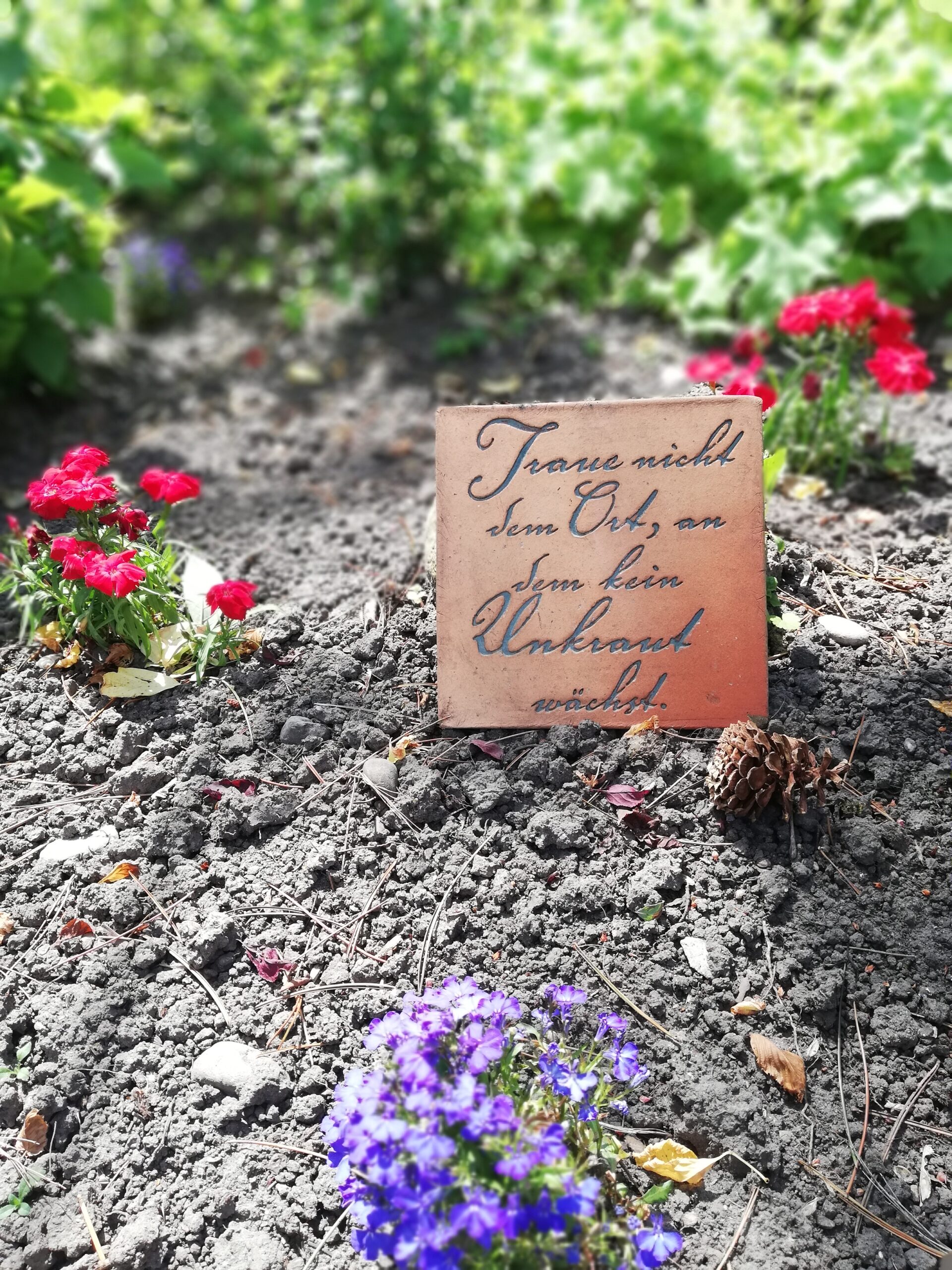 Blumenbeet und Dekoschild im Hotelgarten