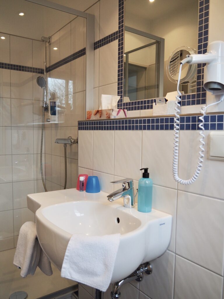 Badezimmer mit Föhn und Dusche im Hotelzimmer des Hotel Friesenhuus